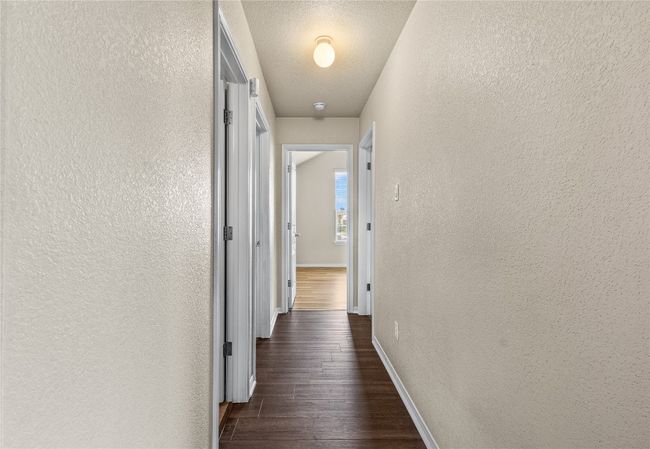 Corridor with a textured wall and dark wood finished floors | Image 24