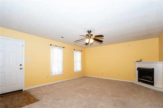 Unfurnished living room with a ceiling fan, a glass covered fireplace, and light colored carpet | Image 6
