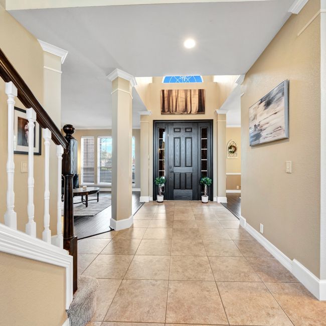 Entrance foyer featuring decorative columns, stairway, baseboards, and tile floors | Image 9
