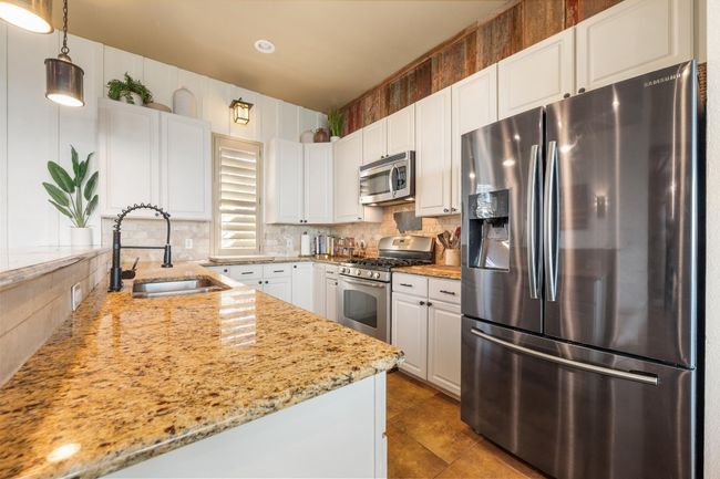 Kitchen with white cabinetry, a sink, stainless steel appliances, and tasteful backsplash | Image 11
