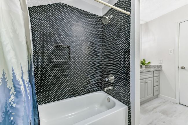 The secondary bathroom features a modern design with a striking black tile accent in tub/shower. | Image 31