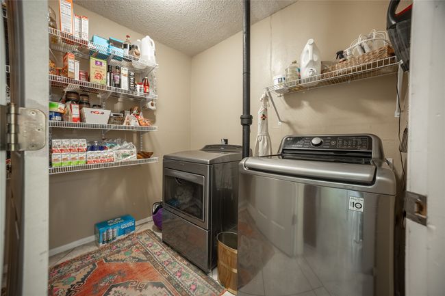 Washroom featuring a textured ceiling, washing machine and clothes dryer, laundry area, and baseboards | Image 11