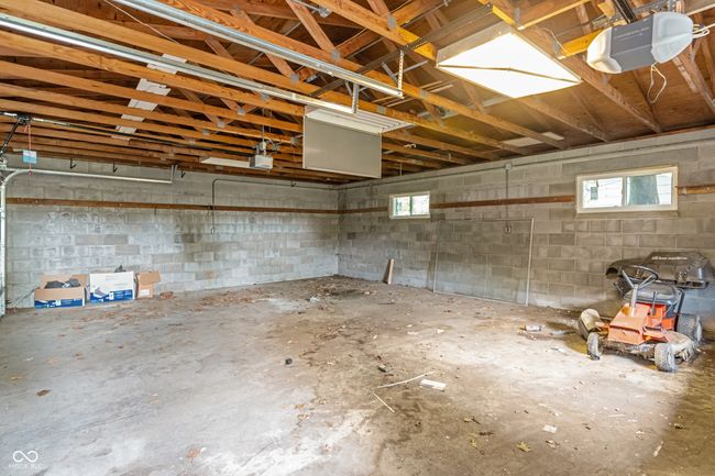 garage featuring a garage door opener and concrete block wall | Image 48