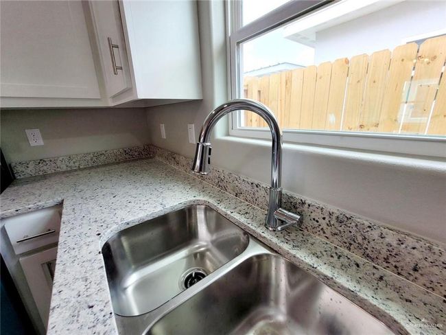 Interior details featuring white cabinets, light stone counters, and a sink | Image 8
