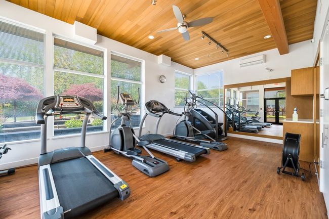 Gym with a wall mounted air conditioner, wooden ceiling, ceiling fan, and wood finished floors | Image 23