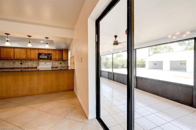 Kitchen featuring electric stove, brown cabinets, ceiling fan, black microwave, and light tile patterned flooring | Image 37