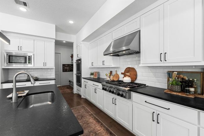 Apron gas cooktop and double ovens offered in this sleek yet functional kitchen. | Image 18