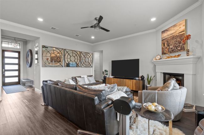 Living area featuring dark wood finished floors, recessed lighting, a glass covered fireplace, a ceiling fan, and crown molding | Image 12