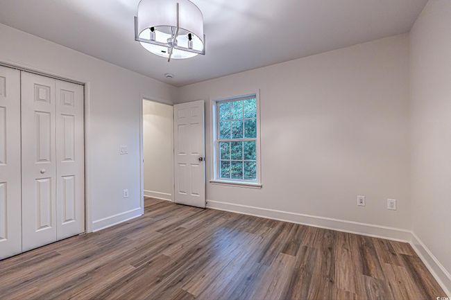 Unfurnished bedroom with wood finished floors, a closet, and a chandelier | Image 31