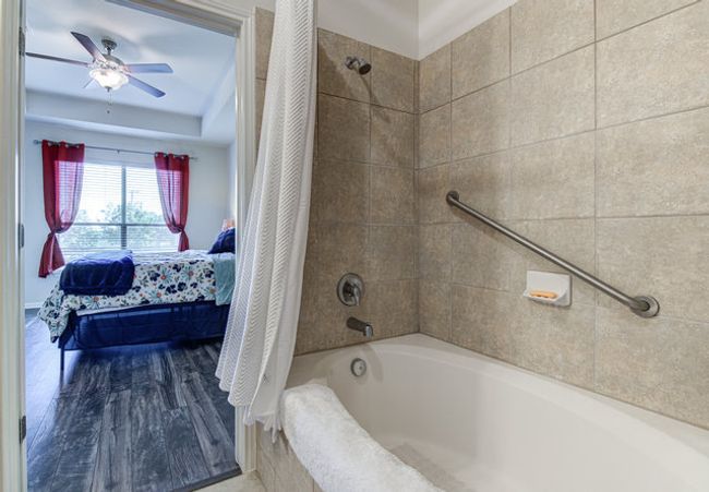 Bathroom featuring shower / bath combo with shower curtain, ensuite bath, a raised ceiling, and a ceiling fan | Image 11