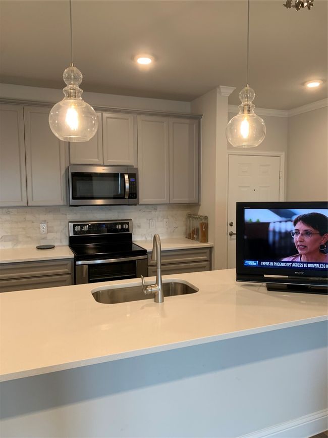 Kitchen with gray cabinetry, stove, tasteful backsplash, light countertops, and recessed lighting | Image 5