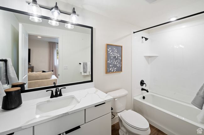 Ensuite bathroom featuring toilet, vanity, wood finished floors, and tub / shower combination | Image 24