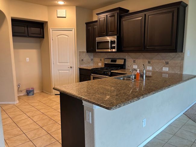 Kitchen with stainless steel appliances, a peninsula, a sink, and light tile patterned flooring | Image 24