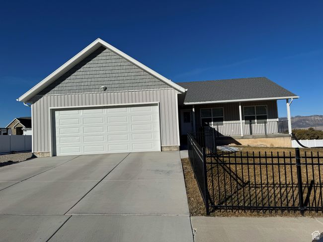 Ranch-style home with a garage, concrete driveway, a fenced front yard, covered porch, and board and batten siding | Image 4