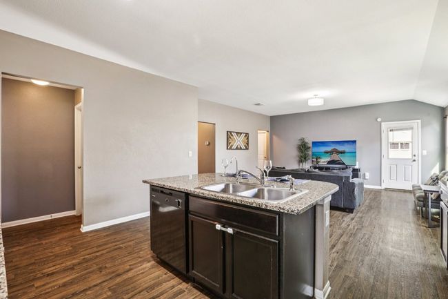 Kitchen with dishwasher, open floor plan, dark wood-style floors, an island with sink, and lofted ceiling | Image 9