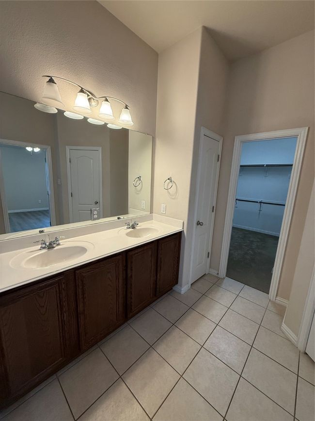 Full bath featuring a sink, tile patterned floors, double vanity, and baseboards | Image 11