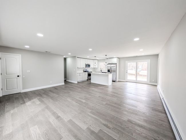 Unfurnished living room with a baseboard heating unit, light wood-type flooring, baseboards, and recessed lighting | Image 4