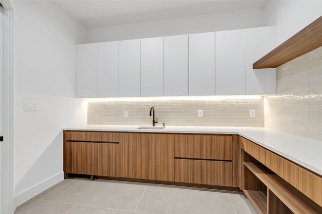 Kitchen featuring modern cabinets, light countertops, backsplash, and white cabinets | Image 19