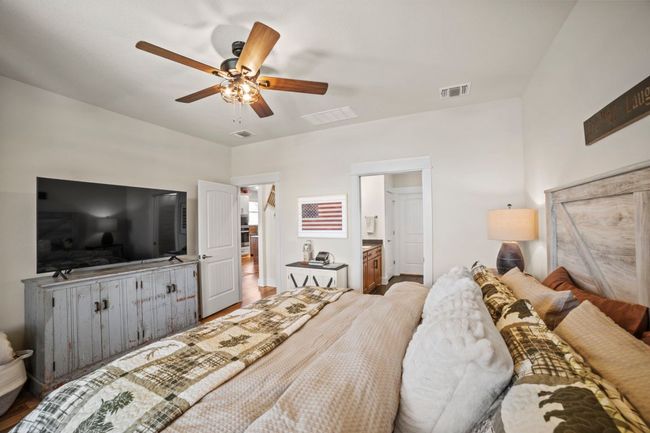 Bedroom with a ceiling fan, visible vents, and ensuite bathroom | Image 22