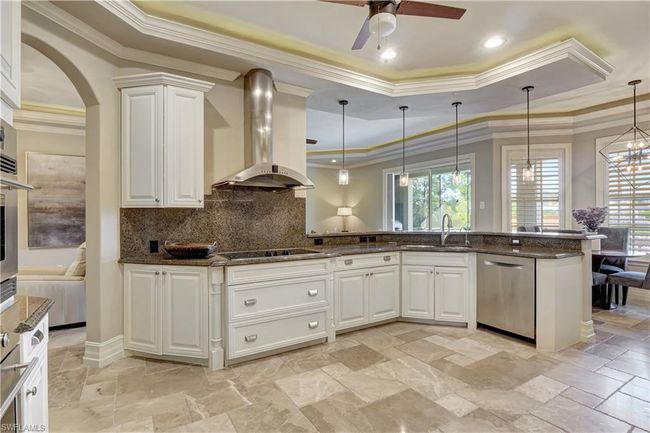 Kitchen featuring dishwasher, a sink, ventilation hood, a raised ceiling, and crown molding | Image 16