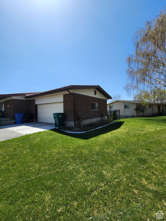 View of side of property with a lawn, an attached garage, concrete driveway, and brick siding | Image 57
