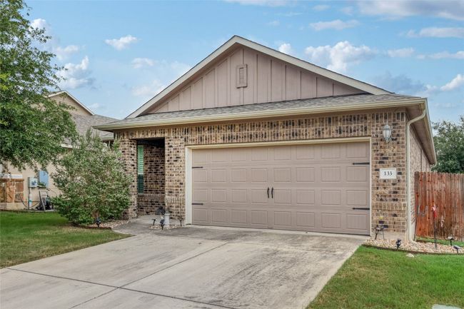 Single story home with brick siding, board and batten siding, concrete driveway, an attached garage, and roof with shingles | Image 29