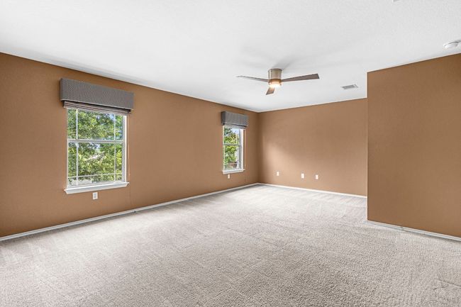 Empty room with a wall mounted AC, a ceiling fan, and carpet flooring | Image 22