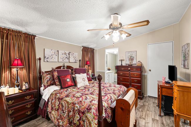 Bedroom with wood finished floors, a textured ceiling, vaulted ceiling, ceiling fan, and ensuite bathroom | Image 23