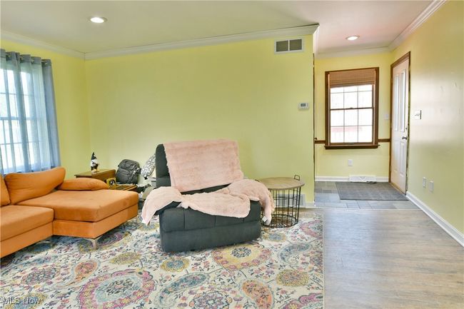 Living area with baseboards, ornamental molding, visible vents, and wood finished floors | Image 22