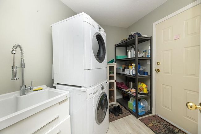 Laundry area featuring light wood-type flooring, laundry area, a sink, and stacked washer / drying machine | Image 13