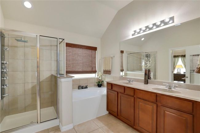 Bathroom featuring lofted ceiling, a shower stall, a garden tub, double vanity, and tile patterned floors | Image 15