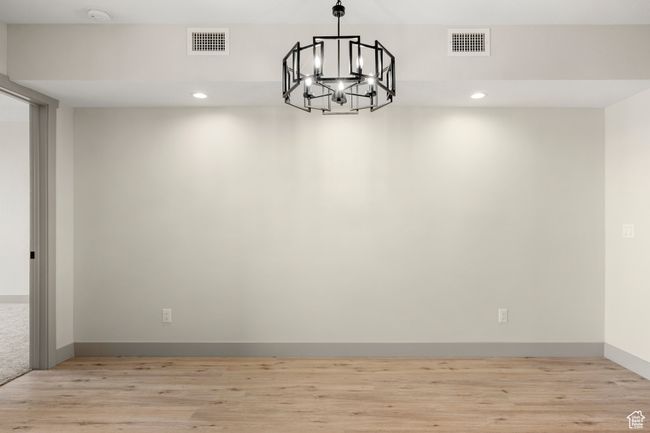 Unfurnished room featuring a chandelier, light wood finished floors, recessed lighting, a smoke detector, and baseboards | Image 9