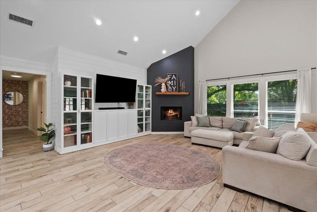 Cozy living space with vaulted ceiling, fireplace accent wall, and built-in media storage. | Image 18