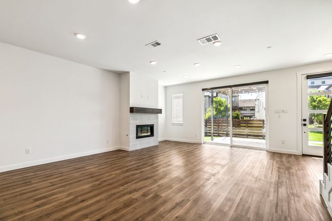 Unfurnished living room with baseboards, wood finished floors, a tiled fireplace, and recessed lighting | Image 9