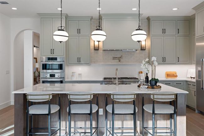 Kitchen featuring wood finished floors, stainless steel double oven, light countertops, arched walkways, and recessed lighting | Image 18