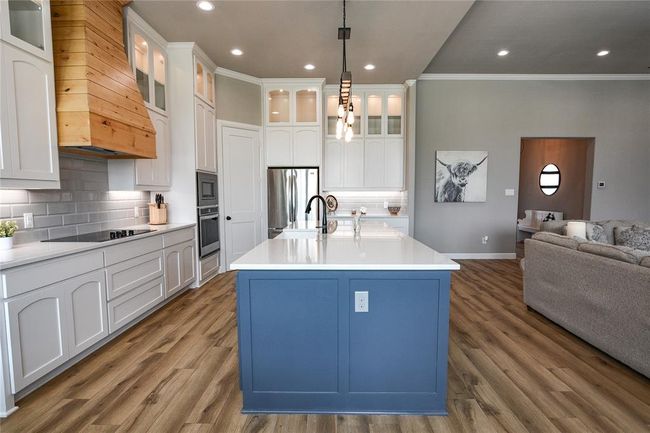 Kitchen with appliances with stainless steel finishes, an island with sink, tasteful backsplash, and wood-style floors | Image 9