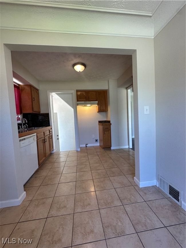 Kitchen featuring visible vents, light tile patterned flooring, dark countertops, and dishwasher | Image 15