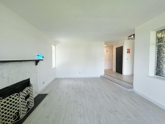 Unfurnished living room featuring wood finished floors and a high end fireplace | Image 5