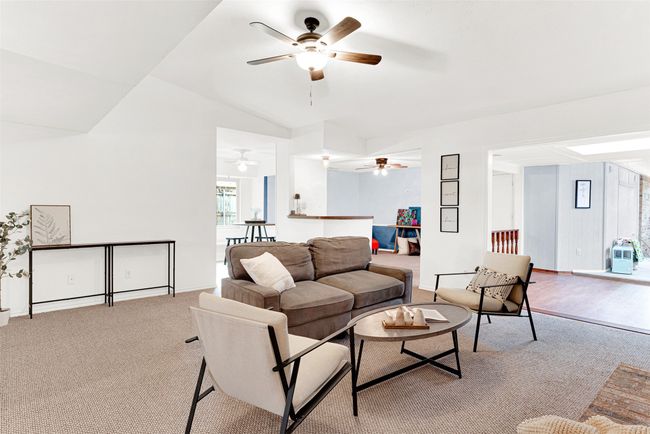 Carpeted living room featuring ceiling fan and vaulted ceiling | Image 6