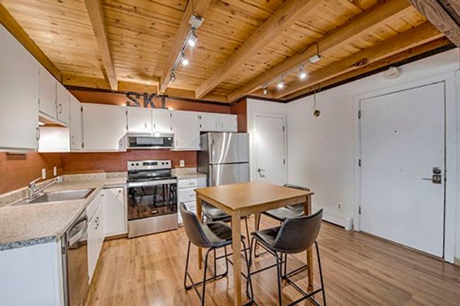 Kitchen with stainless steel appliances, a sink, track lighting, wooden ceiling, and light wood finished floors | Image 5
