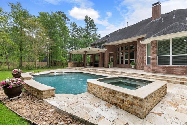 Two covered patio areas with outdoor kitchen and large decked entertainment area, leading to a beautiful sparkling pool and spa. Pool bath is located at rear of home spa side with direct access from pool area. | Image 4