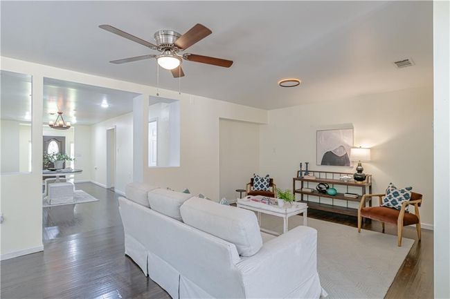 Living room featuring dark wood-type flooring and ceiling fan with notable chandelier | Image 15
