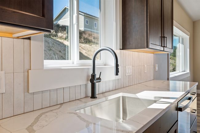 Kitchen with a sink, dark brown cabinetry, tasteful backsplash, and light stone countertops | Image 16