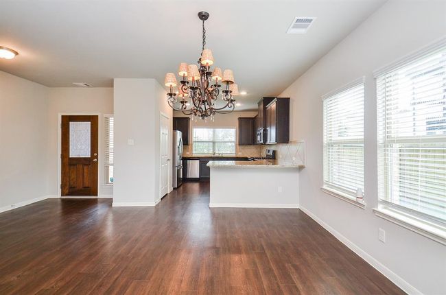 Shining wood? wood laminate? wood look tile? flooring warms this huge living/family/kitchen space, with complementing pale walls and large windows. | Image 5