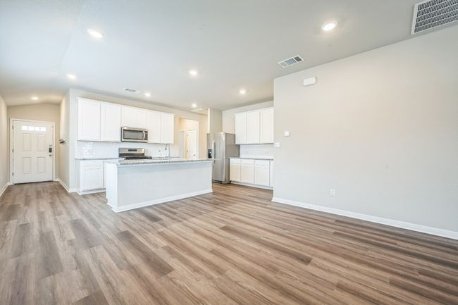 Kitchen featuring stainless steel appliances, light wood-style flooring, an island with sink, recessed lighting, and white cabinets | Image 8