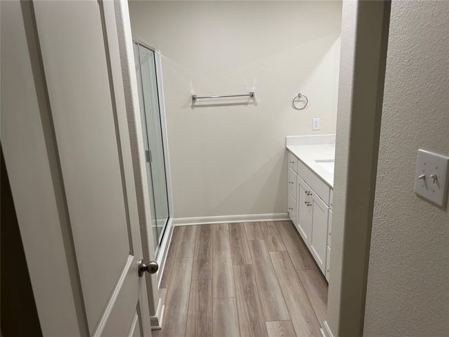 Full bathroom featuring vanity, a shower stall, wood finished floors, and baseboards | Image 7