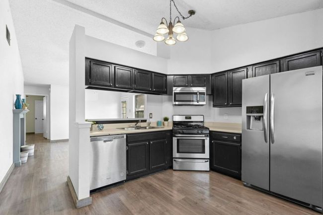 Kitchen featuring appliances with stainless steel finishes, dark cabinets, decorative light fixtures, light countertops, and high vaulted ceiling | Image 11