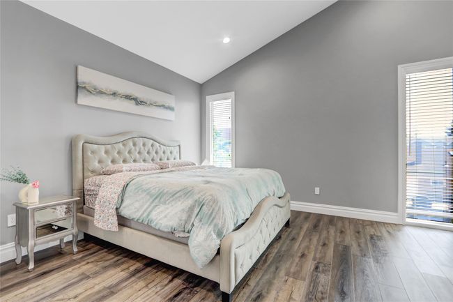 Bedroom with lofted ceiling, wood finished floors, baseboards, and recessed lighting | Image 15