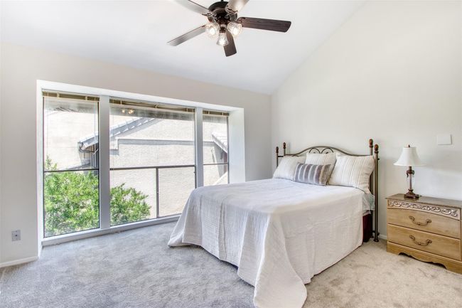 Bedroom with multiple windows, light carpet, vaulted ceiling, and a ceiling fan | Image 19