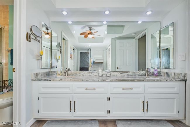 Bathroom with double vanity, a tile shower, ceiling fan, and wood finished floors | Image 22
